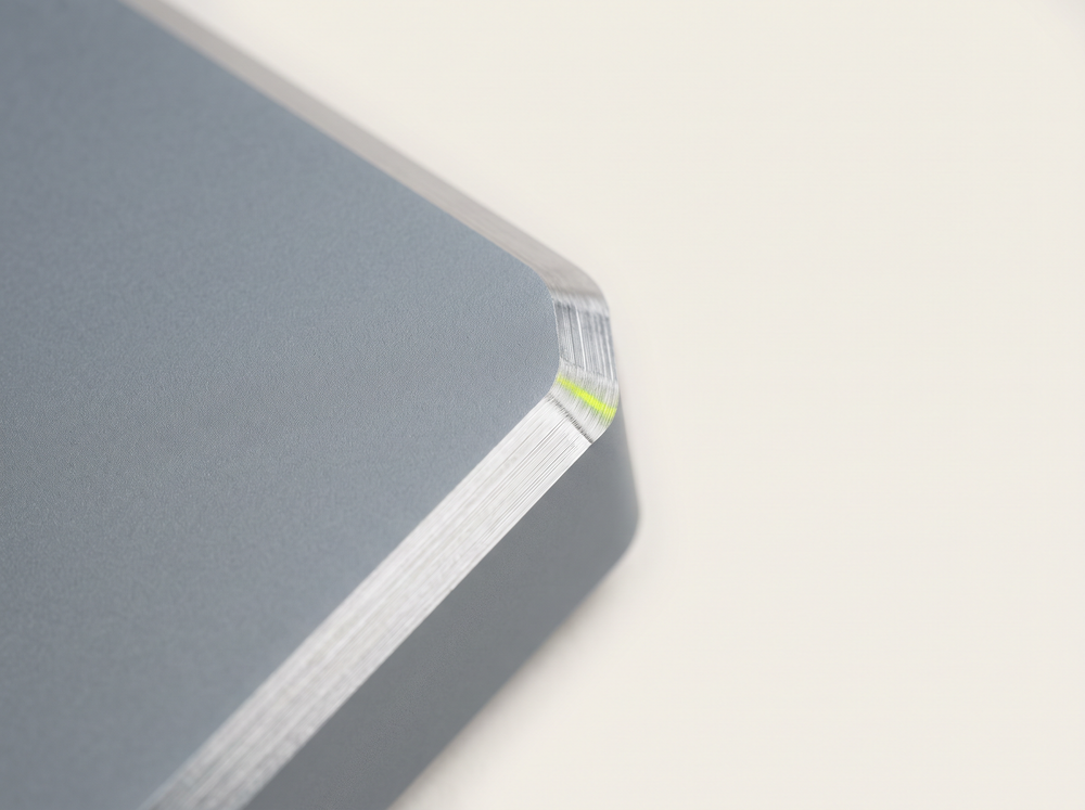 A metal corner where a matte grey surface meets a bright chamfer of raw metal.
