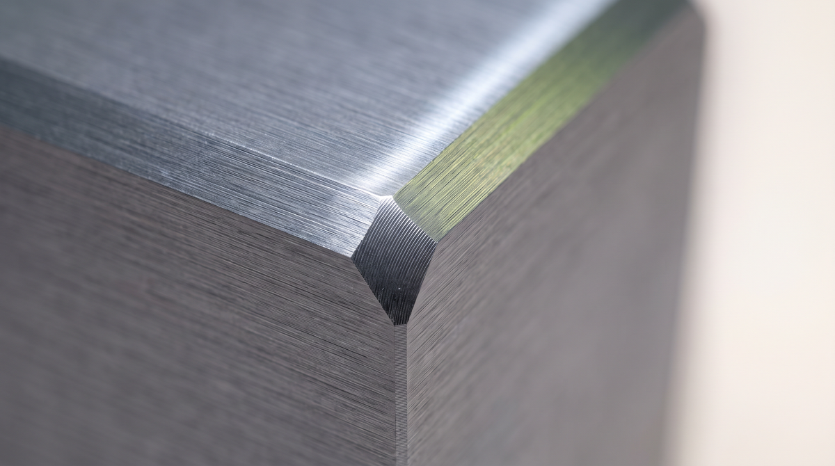 Macro detail of a brushed metal surface meeting a chamfered edge.